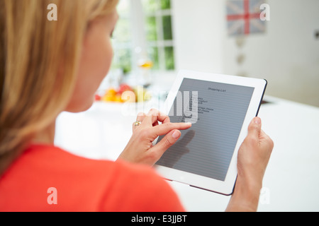 Donna con tavoletta digitale per scrivere la lista della spesa a casa Foto Stock