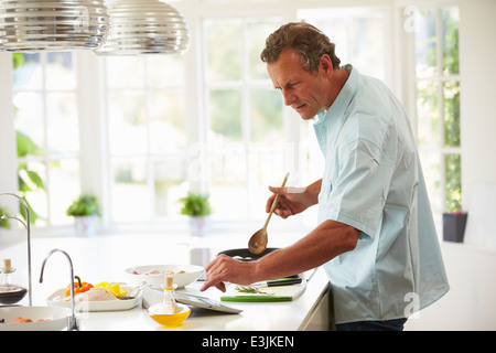Uomo di mezza età seguente ricetta sulla tavoletta digitale Foto Stock