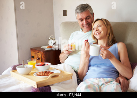 Prima colazione a letto: Donne sdraiate a letto con una tazza di caffè,  vassoio con croissant e vasetto di marmellata Foto stock - Alamy