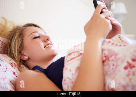 Ragazza adolescente Invio messaggio di testo mentre ero a letto Foto Stock
