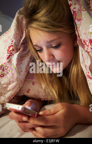 Infelice ragazza adolescente Invio messaggio di testo mentre ero a letto Foto Stock