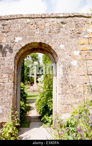 Guardando attraverso un portale in pietra in un giardino segreto di un maniero di campagna inglese in estate Foto Stock