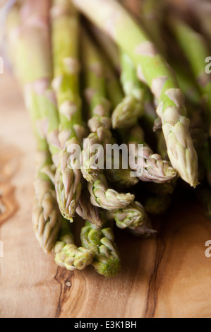 Freschi asparagi organico affastellati assieme su un tagliere di legno Foto Stock