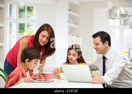 Famiglia utilizzando dispositivi digitali a tavolo per la colazione Foto Stock