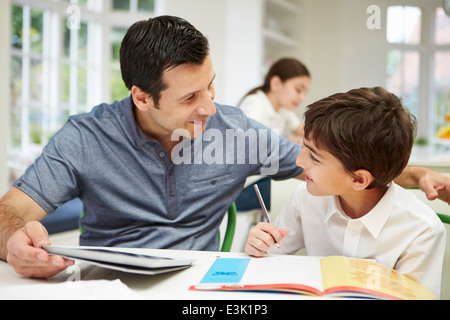 Padre aiutando figlio con i compiti utilizzando tavoletta digitale Foto Stock