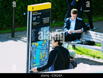 Uomo asiatico con bambino la consultazione di una mappa e di punto di informazione sul Bankside vicino al Millennium Bridge di Londra Inghilterra Europa Foto Stock