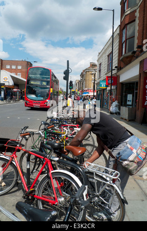 Un uomo si sblocca la sua bicicletta sulla Kingsland Road, Dalston, Hackney, East London E8, England Regno Unito KATHY DEWITT Foto Stock