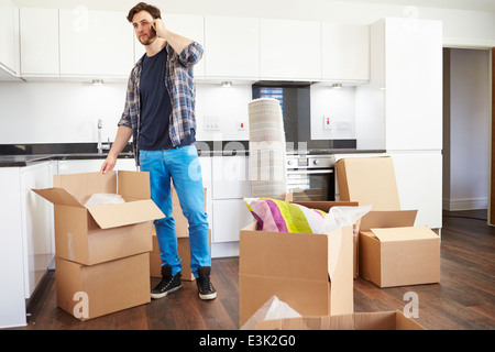 Uomo che si muove nella nuova casa parlando al telefono cellulare Foto Stock