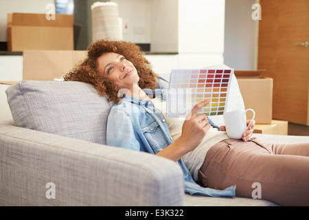 Donna seduta sul divano guardando i grafici di vernice Foto Stock