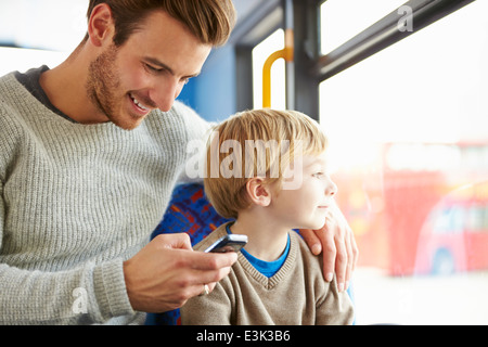 Padre utilizzando il telefono cellulare sul viaggio in autobus con figlio