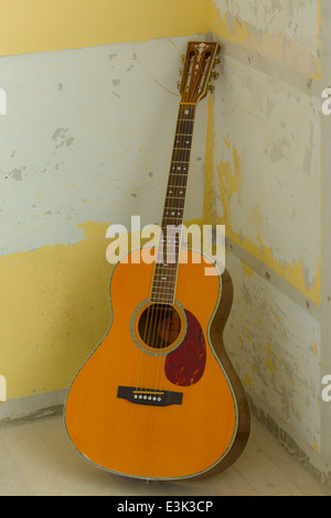Una chitarra acustica in un angolo di una stanza Foto Stock