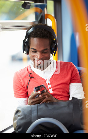 Uomo che indossa le cuffie per ascoltare musica in viaggio in autobus Foto Stock