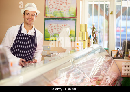 Butcher durante il lavoro nel negozio Foto Stock