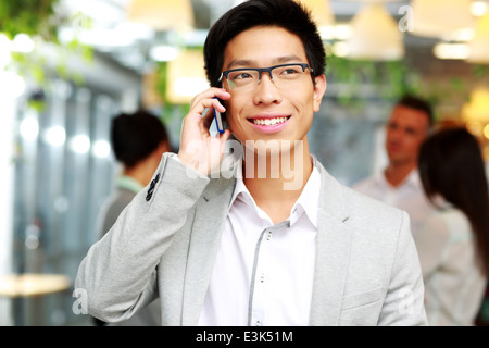 Ritratto di un happy businessman parlando sullo smartphone di fronte ai colleghi Foto Stock