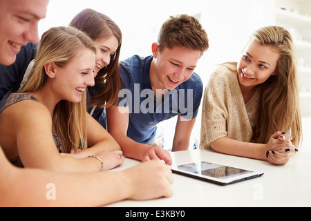 Un gruppo di ragazzi riuniti attorno a tavoletta digitale insieme Foto Stock