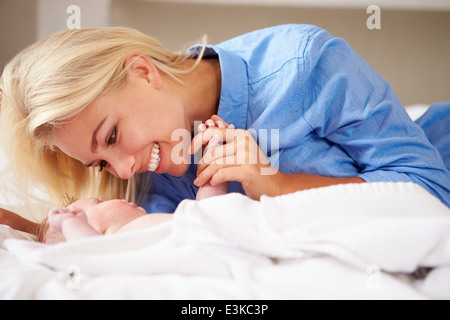 Madre giocando con la bambina che giacciono nel letto insieme Foto Stock