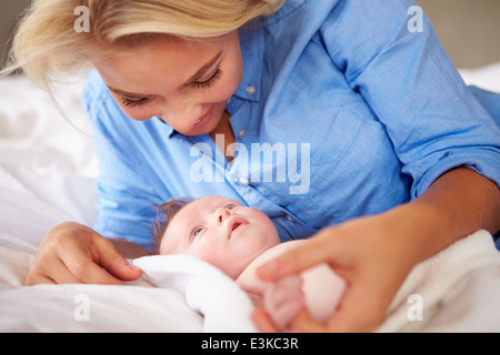 Madre giocando con la bambina che giacciono nel letto insieme Foto Stock