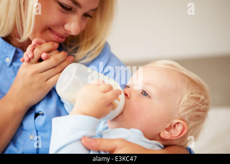 Madre dando Baby figlio bottiglia di latte Foto Stock