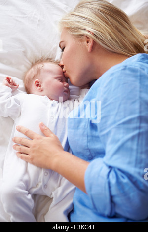 Madre baciare Bambina che giacciono nel letto insieme Foto Stock