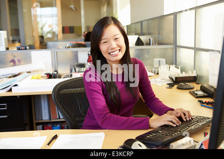 Donna asiatica lavora al computer in un ufficio moderno Foto Stock