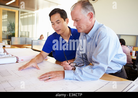 Architetti studiando piani in un ufficio moderno insieme Foto Stock