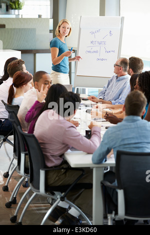 Imprenditrice affrontando riuniti attorno al tavolo della sala riunioni Foto Stock