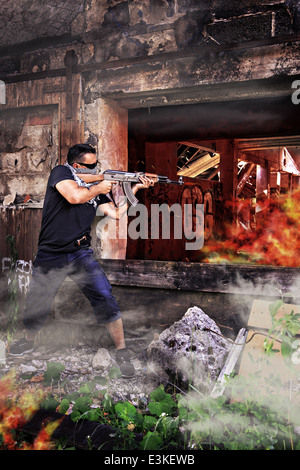 Militante mascherata con un mitragliatore eseguendo street battaglia Foto Stock