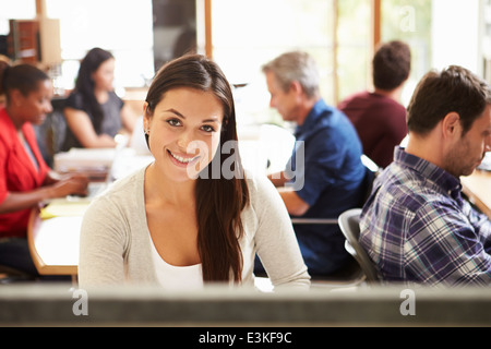 Architetto femmina lavorare alla scrivania con sale riunioni in background Foto Stock