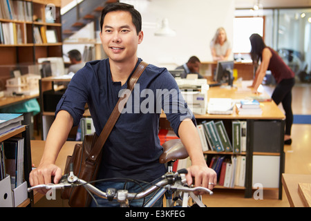 Architetto arriva a lavorare sulla moto spingendolo attraverso Office Foto Stock