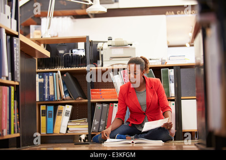 Imprenditrice seduta sul pavimento di Office la lettura dei documenti Foto Stock