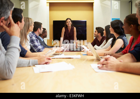 Femmina indirizzamento Boss riuniti attorno al tavolo della sala riunioni Foto Stock