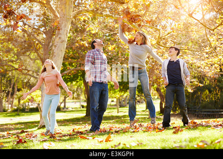 Famiglia di gettare le foglie di autunno in aria Foto Stock