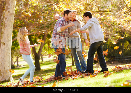 Famiglia di gettare le foglie di autunno in aria Foto Stock