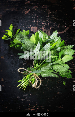 Mazzetto di menta fresca su tavoli in legno nero. Vista dall'alto. Foto Stock