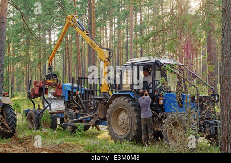 Rottura del trattore in legno. Il trattore arare un solco di divisione luoghi di foresta a firestorm. Foto Stock