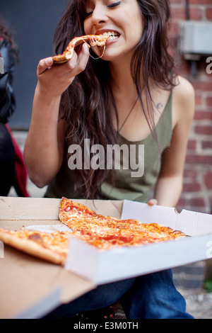 Giovane donna adulta mangiare la pizza Foto Stock
