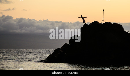 Cliff Diver salta fuori Black Rock a Kaanapali Beach durante il notturno Tramonto Cerimonia Foto Stock