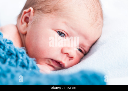 Piccolo bambino avvolto in tessuto a maglia che giace sul morbido letto bianco Foto Stock