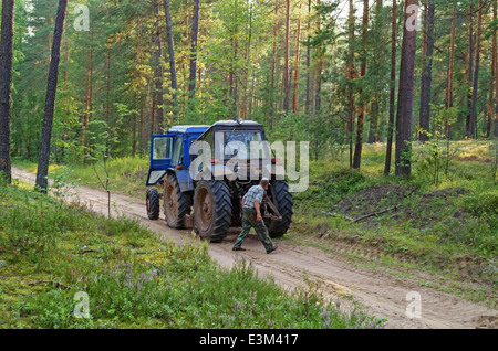 Rottura del trattore in legno. Il trattore arare un solco di divisione luoghi di foresta a firestorm. Foto Stock