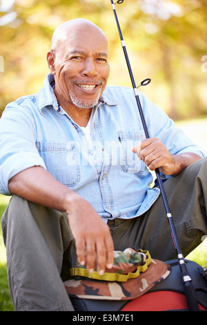 Senior uomo sulla vacanza in campeggio con la canna da pesca Foto Stock