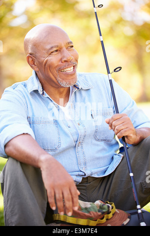 Senior uomo sulla vacanza in campeggio con la canna da pesca Foto Stock