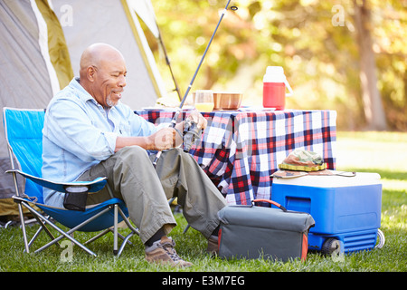 Senior uomo sulla vacanza in campeggio con la canna da pesca Foto Stock