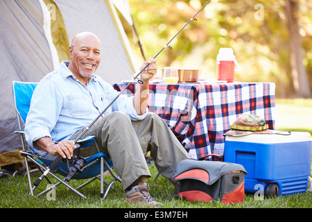 Senior uomo sulla vacanza in campeggio con la canna da pesca Foto Stock