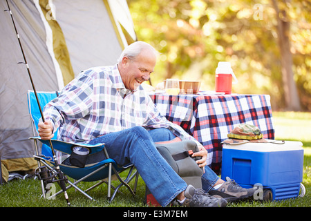 Senior uomo sulla vacanza in campeggio con la canna da pesca Foto Stock