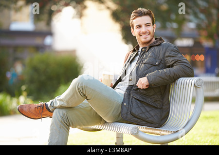 Uomo relax su una panchina nel parco con caffè da asporto Foto Stock