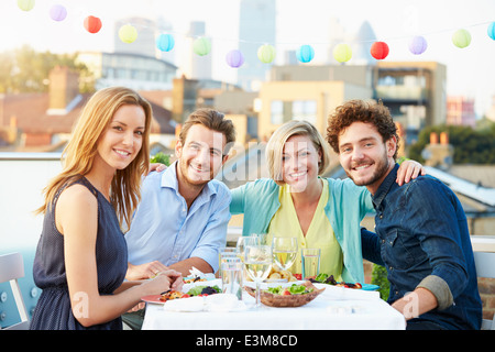 Gruppo di amici di mangiare pasti sulla terrazza sul tetto Foto Stock