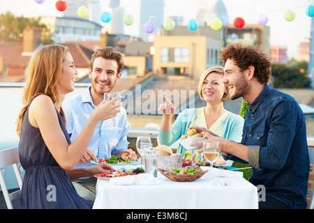 Gruppo di amici di mangiare pasti sulla terrazza sul tetto Foto Stock