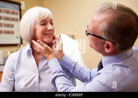 Chirurgo cosmetico esaminando Senior Client femmina in Office Foto Stock