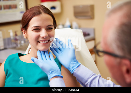 Chirurgo cosmetico esaminando femmina nel client di Office Foto Stock