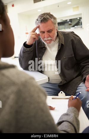 Uomo che parla al consulente che prende appunti Foto Stock